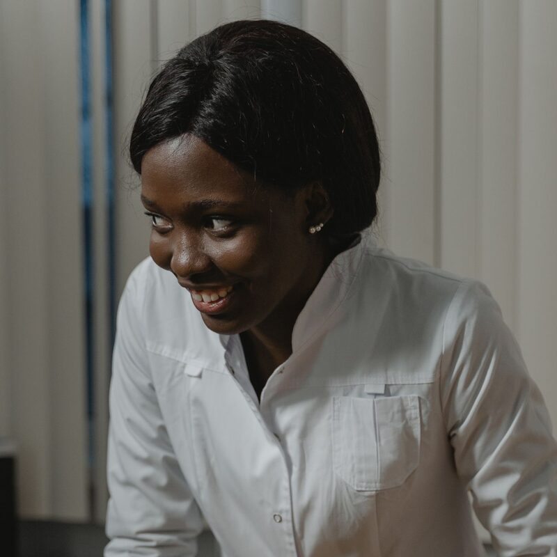 Dr. Ada Okafor in a white clinic coat, smiling as she examines a fluffy Pomeranian